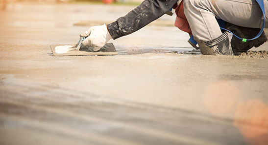 A man kneeling down on the road and working on Concrete Slab Leveling